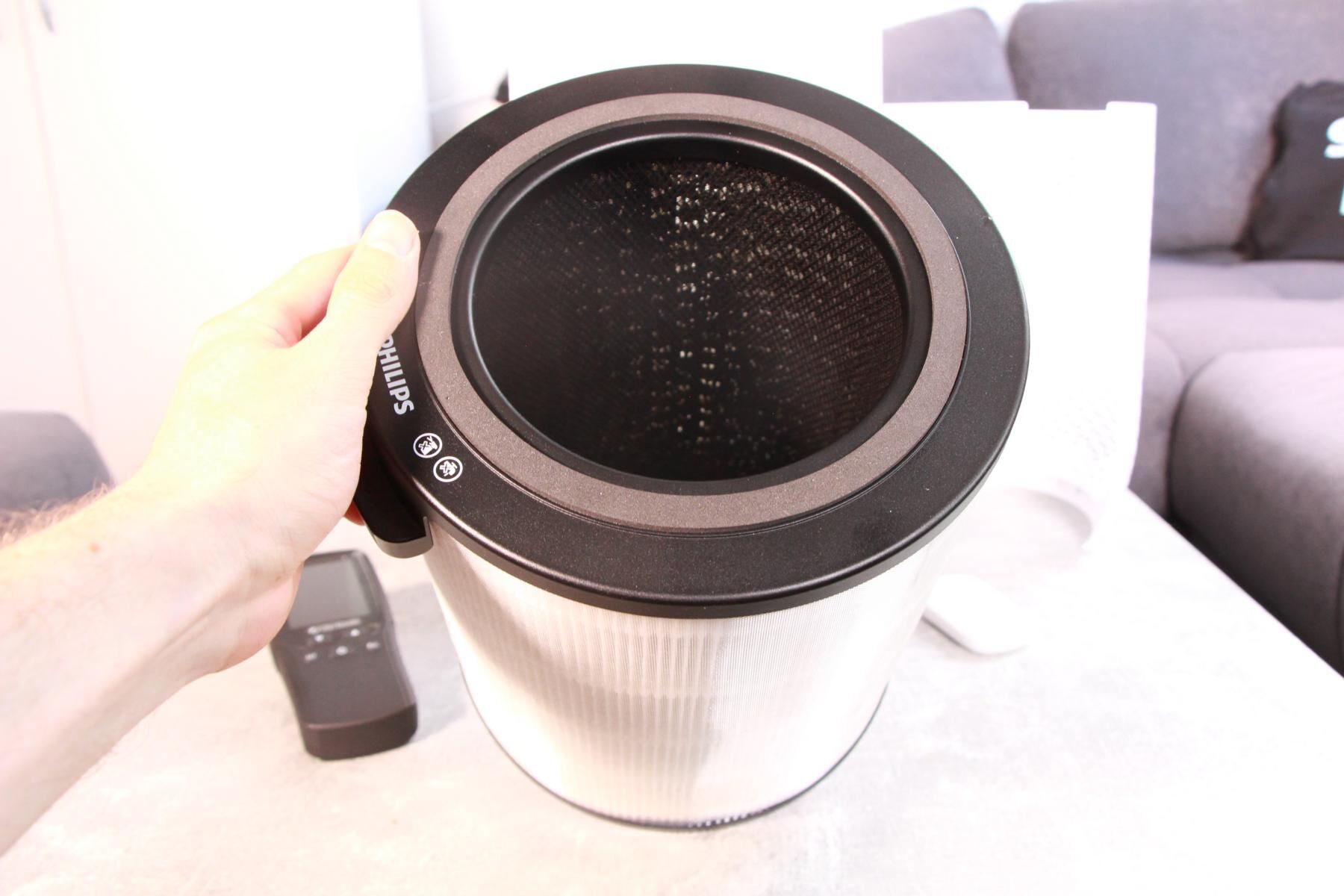 Die Filtereinheit des Philips Air Performer 8000 Luftreinigers wird in der Hand neben dem Gerät gehalten und zu sehen ist der HEPA-Filter außen und der Aktivkohlefilter auf der Innenseite.